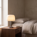 Fiorente mid century glass table lamp with cream mushroom dome glowing warm on a bedroom nightstand