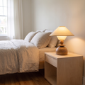 Jouvelle Scandinavian fabric table lamp with beige shade glowing warm on a birch bedroom nightstand