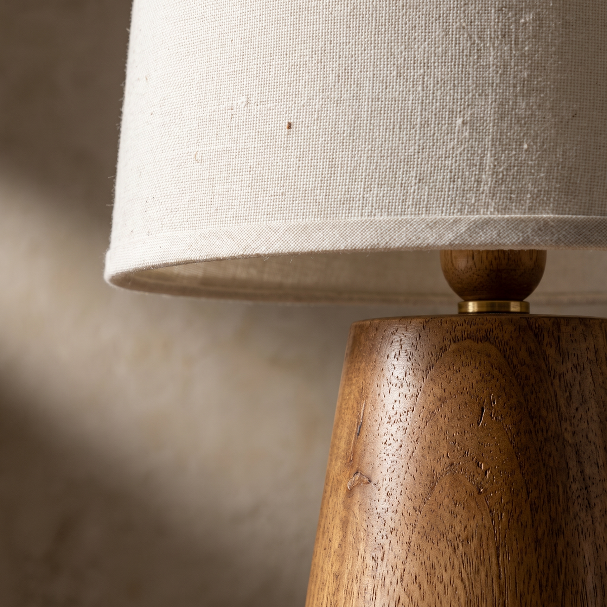 Macro detail of the Velaris table lamp fabric shade weave meeting the natural wood base