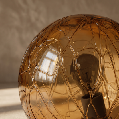 Close-up detail of the Oriane table lamp's tinted amber glass and inner bulb