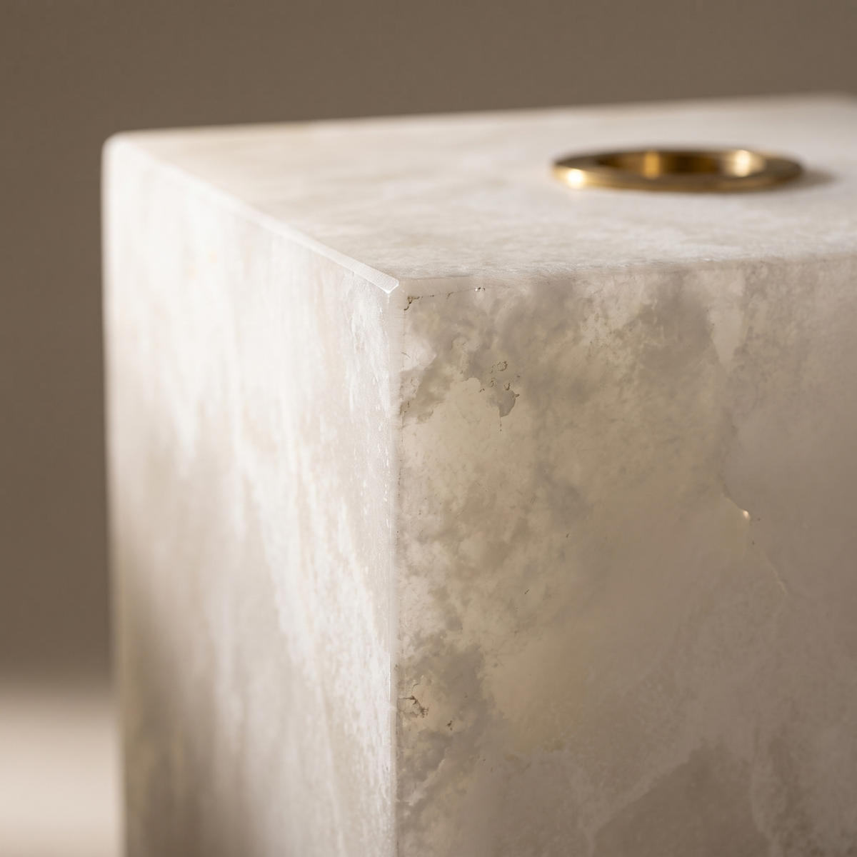 Macro detail of the Duvessa lamp's honed alabaster corner, natural veining and brass ring