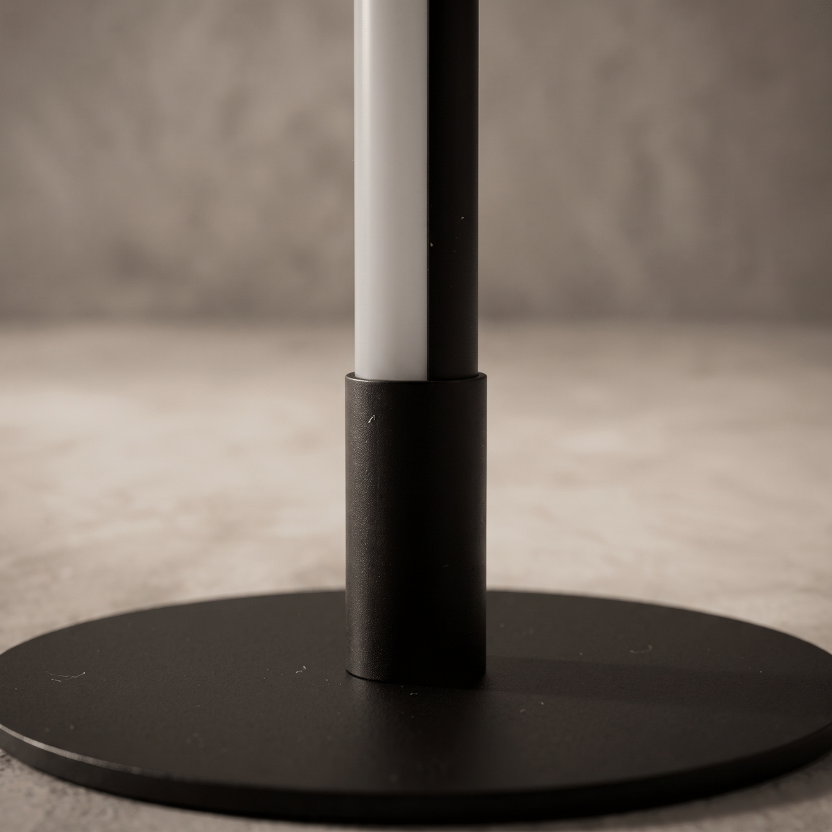 Close-up of the Nervesa table lamp matte black stem frosted LED diffuser and disc base junction