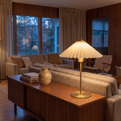 Aurelle fabric table lamp lit at dusk on a walnut living room console beside a sofa