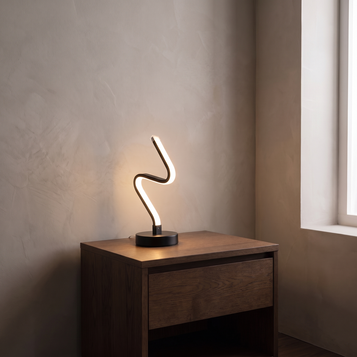 Noirelle modern black aluminum LED table lamp glowing warm on a dark oak bedside nightstand