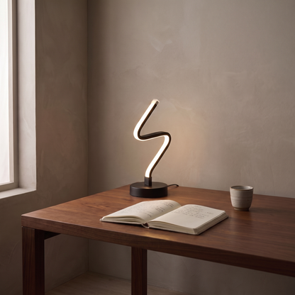 Noirelle compact modern LED table lamp lit on a walnut home office desk at dusk