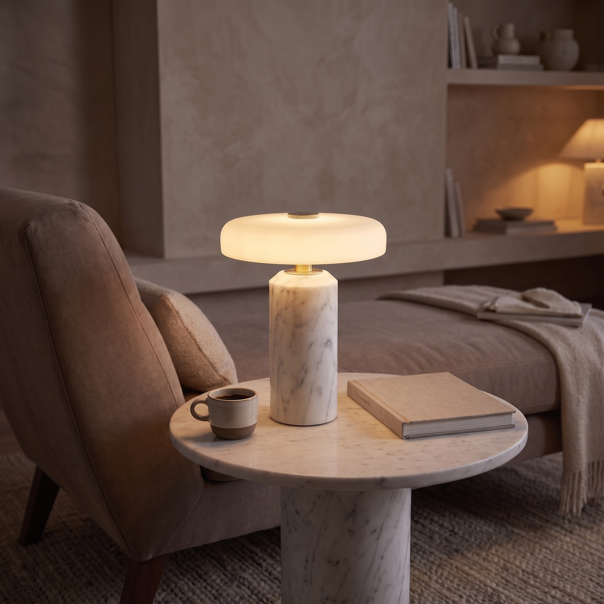 Ophira glass table lamp lit on a marble side table in an elegant lounge at dusk