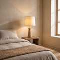 Velaris fabric and wood table lamp glowing warm on a bedside table in a boho modern bedroom