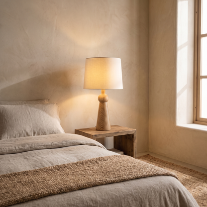 Velaris fabric and wood table lamp glowing warm on a bedside table in a boho modern bedroom