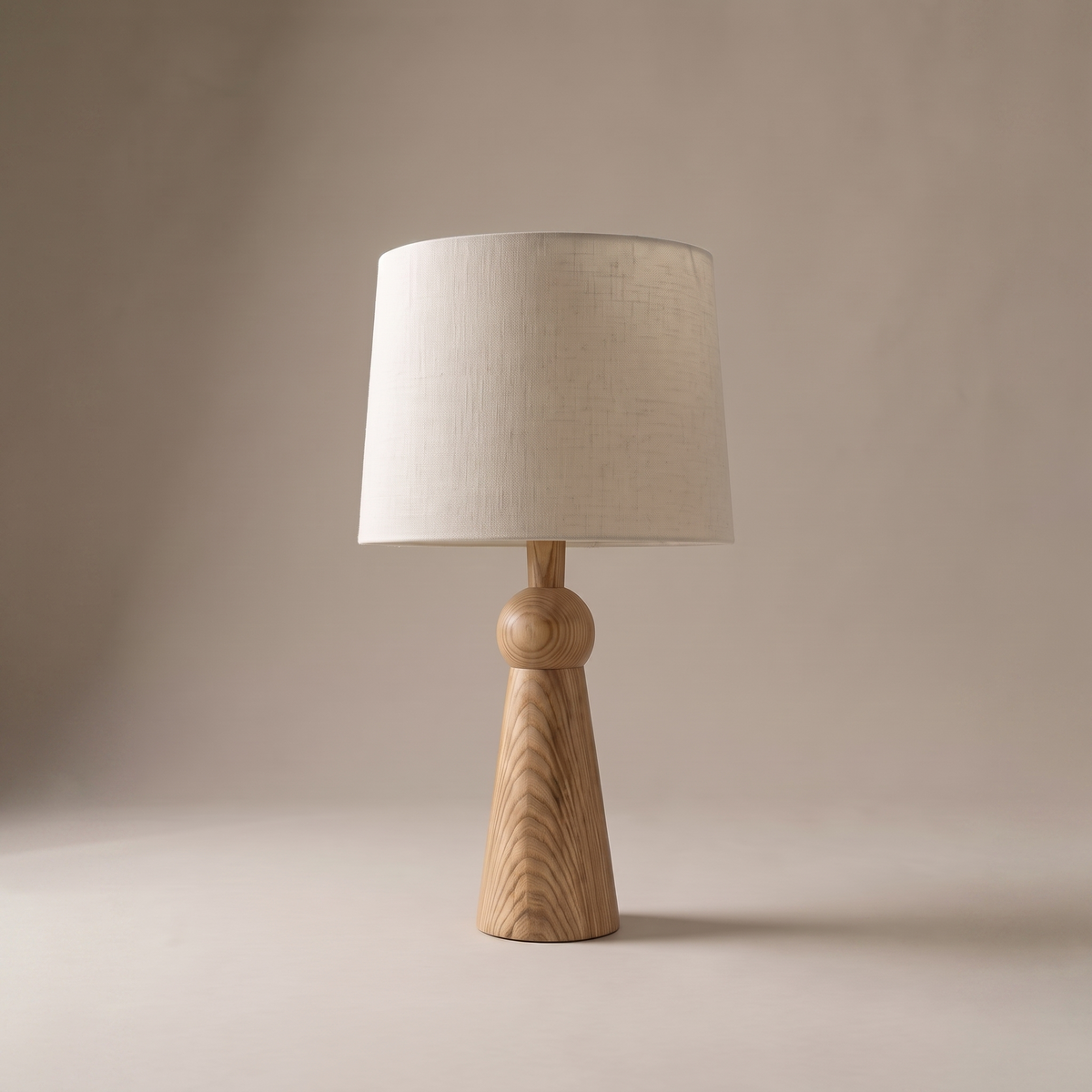 Velaris modern table lamp with wood base and fabric shade, studio shot on warm-greige backdrop, lamp off