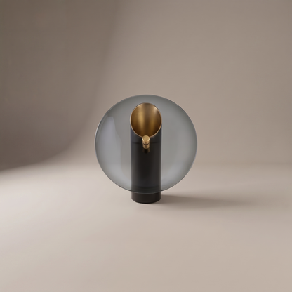 Amberlyn modern table lamp with smoke glass disc and gold-lined black cylinder on a neutral studio backdrop