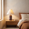 Vionelle contemporary red marble table lamp with cream fabric shade lit on a bedroom nightstand