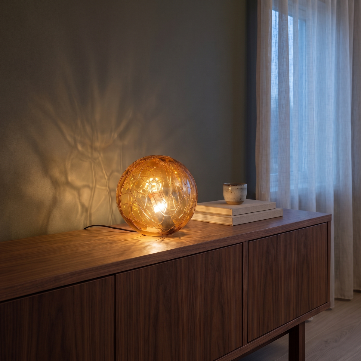 Oriane glass orb table lamp glowing on a walnut living room console at dusk