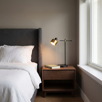 Sablette modern black iron task table lamp with brass head lit on a bedroom nightstand