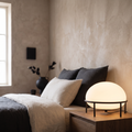 Isolde contemporary black glass and metal table lamp glowing warm on a bedroom nightstand