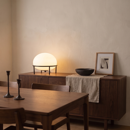 Isolde black table lamp lit at dusk on a walnut sideboard in a contemporary dining room