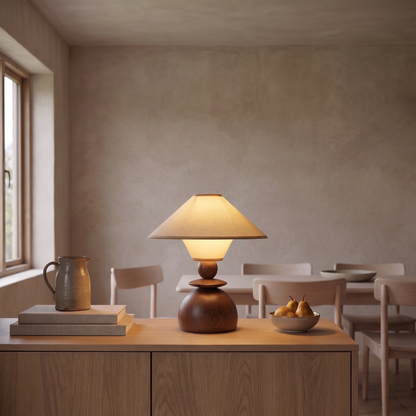 Jouvelle beige fabric table lamp lit at dusk on an oak sideboard in a Scandinavian dining room