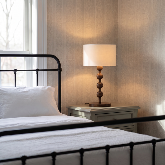 Montrave classic table lamp with turned walnut bobbin base glowing on an elegant bedroom nightstand
