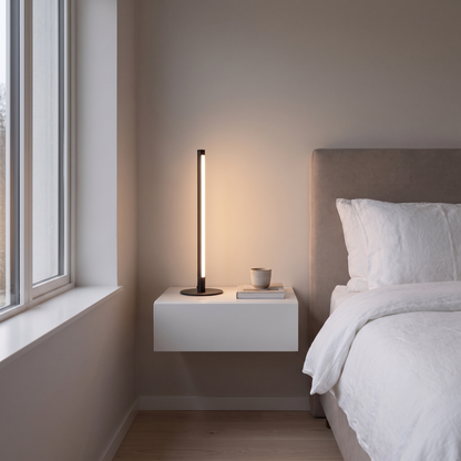 Nervesa modern black LED line table lamp glowing warm on a floating nightstand in a contemporary bedroom