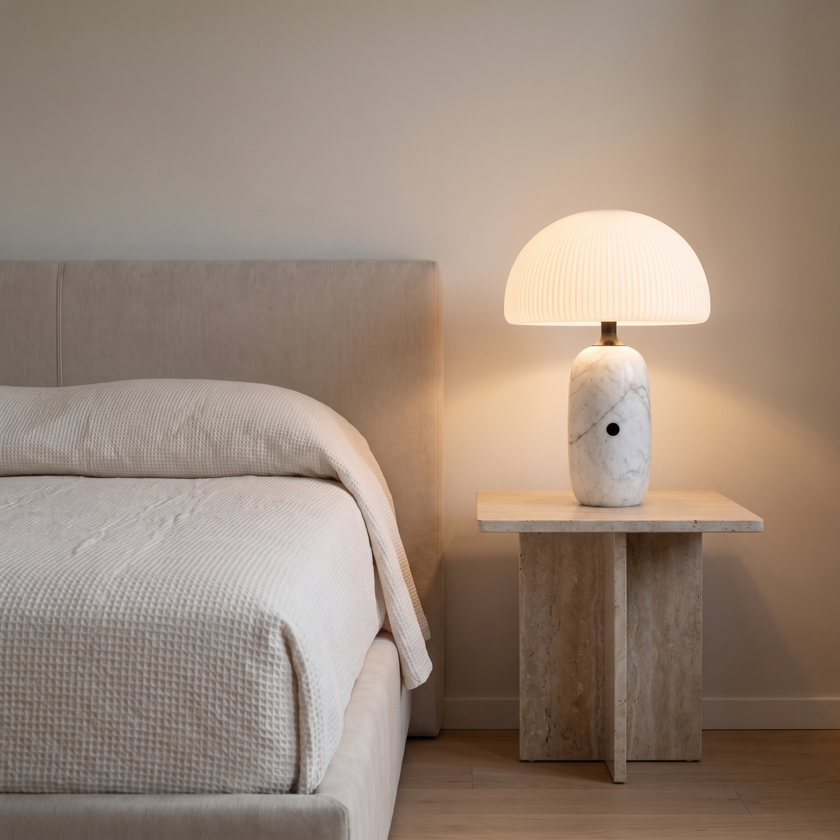 Opaline modern marble table lamp with frosted glass dome glowing on a travertine bedside table