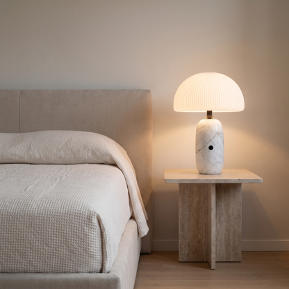 Opaline modern marble table lamp with frosted glass dome glowing on a travertine bedside table