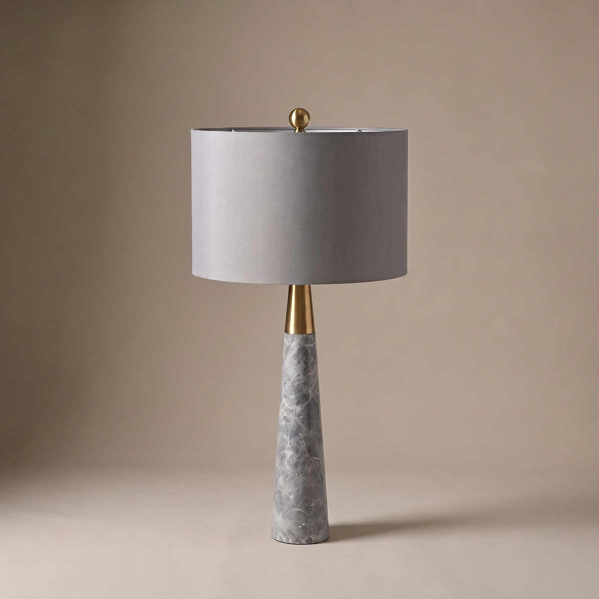 Pravelle table lamp in grey stone and fabric with brass neck, studio product shot on neutral backdrop