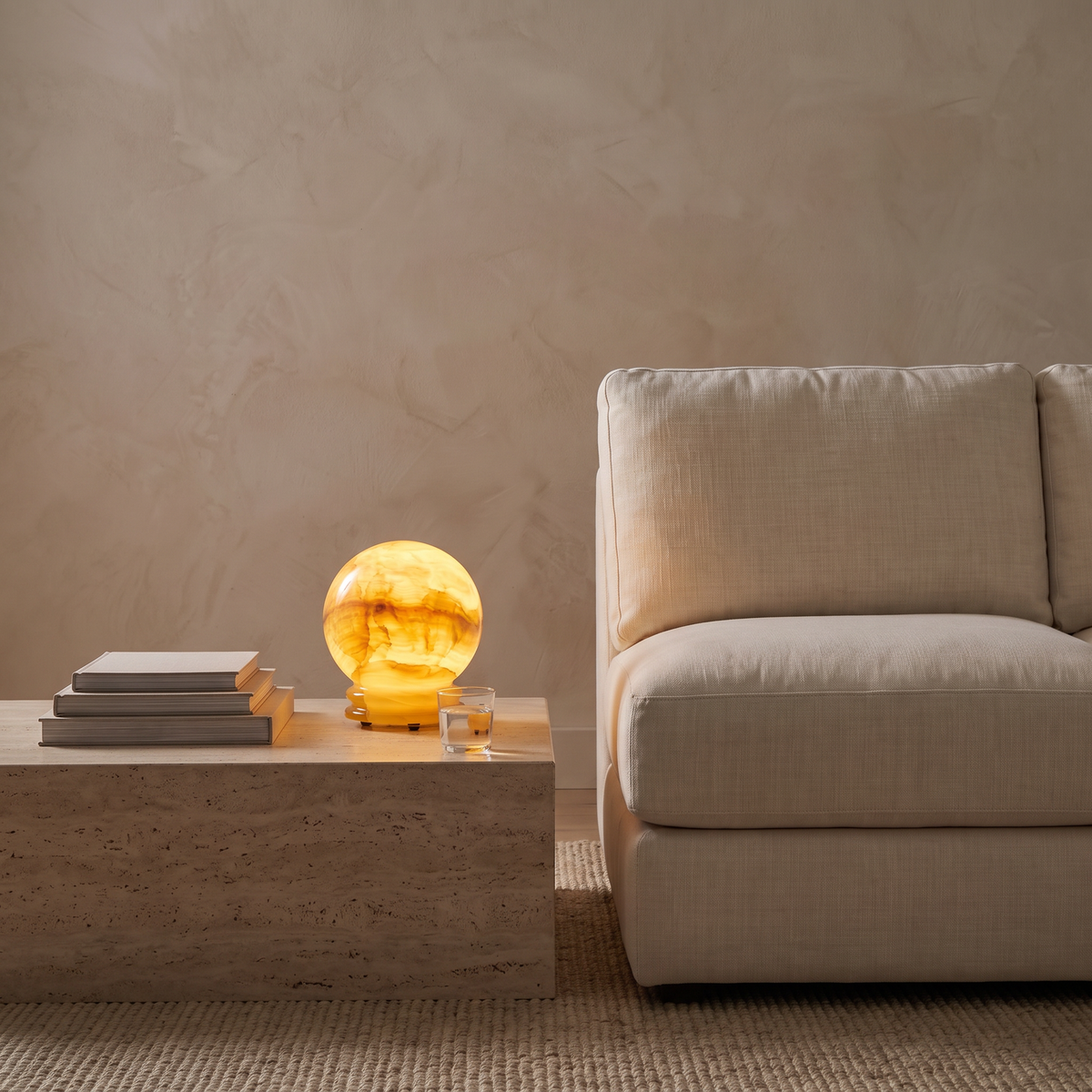 Quillon onyx marble LED table lamp glowing at dusk on a living room side table