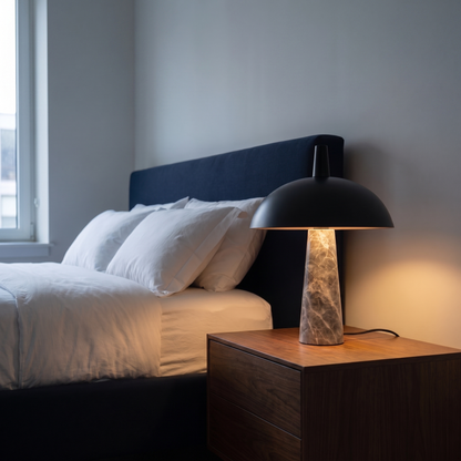 Rosalind modern table lamp with black steel dome and grey marble base lit on a bedroom nightstand