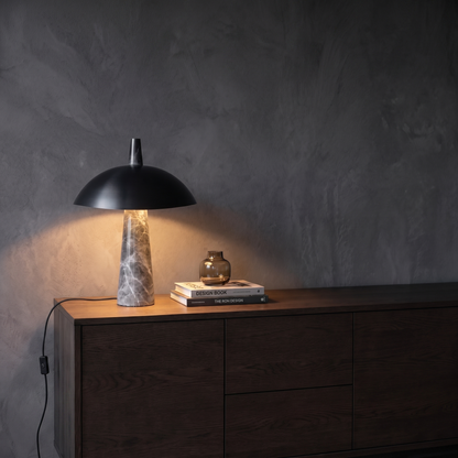Rosalind black dome marble table lamp glowing on a living room sideboard at evening