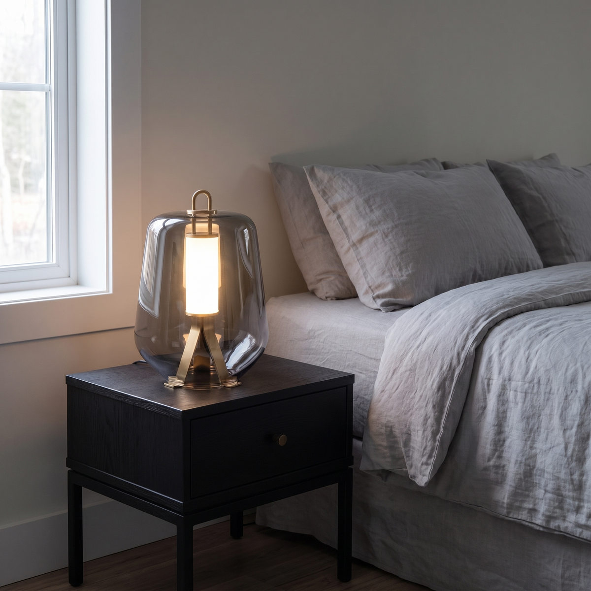 Silverain smoked glass LED table lamp with brass frame glowing on a bedroom nightstand