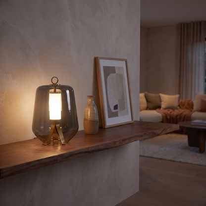 Silverain smoked glass table lamp glowing at dusk on a living room shelf