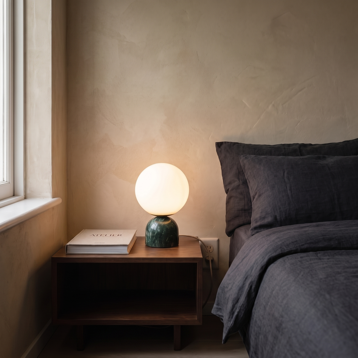 Willowmere green marble and brass table lamp glowing warm on a bedroom nightstand