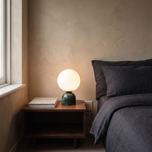 Willowmere green marble and brass table lamp glowing warm on a bedroom nightstand