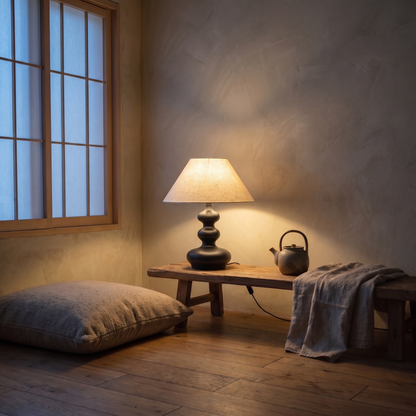 Xanthe boho table lamp lit warm on a low wooden bench in a wabi-sabi living room