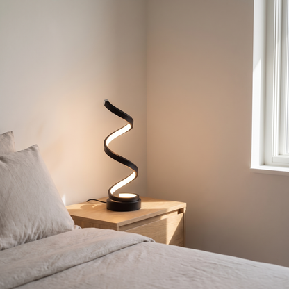 Cordelia modern aluminum LED table lamp glowing warm on a minimalist bedroom nightstand