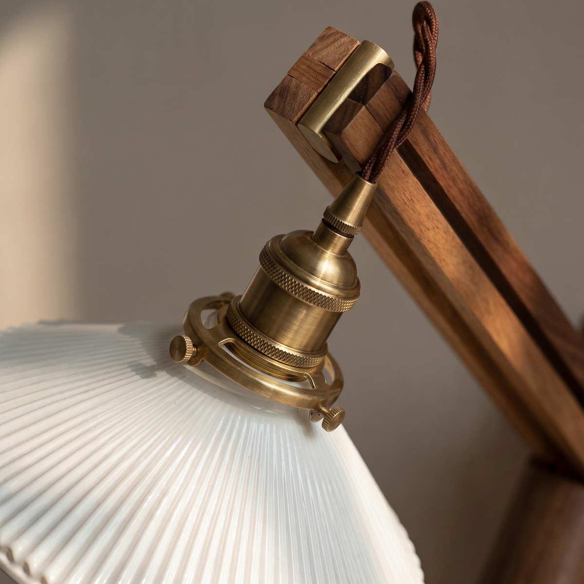 Close-up of brass socket, walnut arm and striped milk white glass shade on the Nordic retractable wall sconce