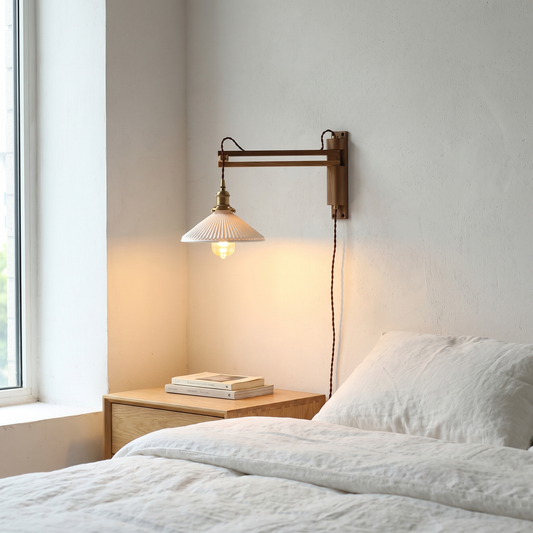 Nordic walnut scissor-arm wall sconce with milk white striped glass shade glowing warm beside an oak bed