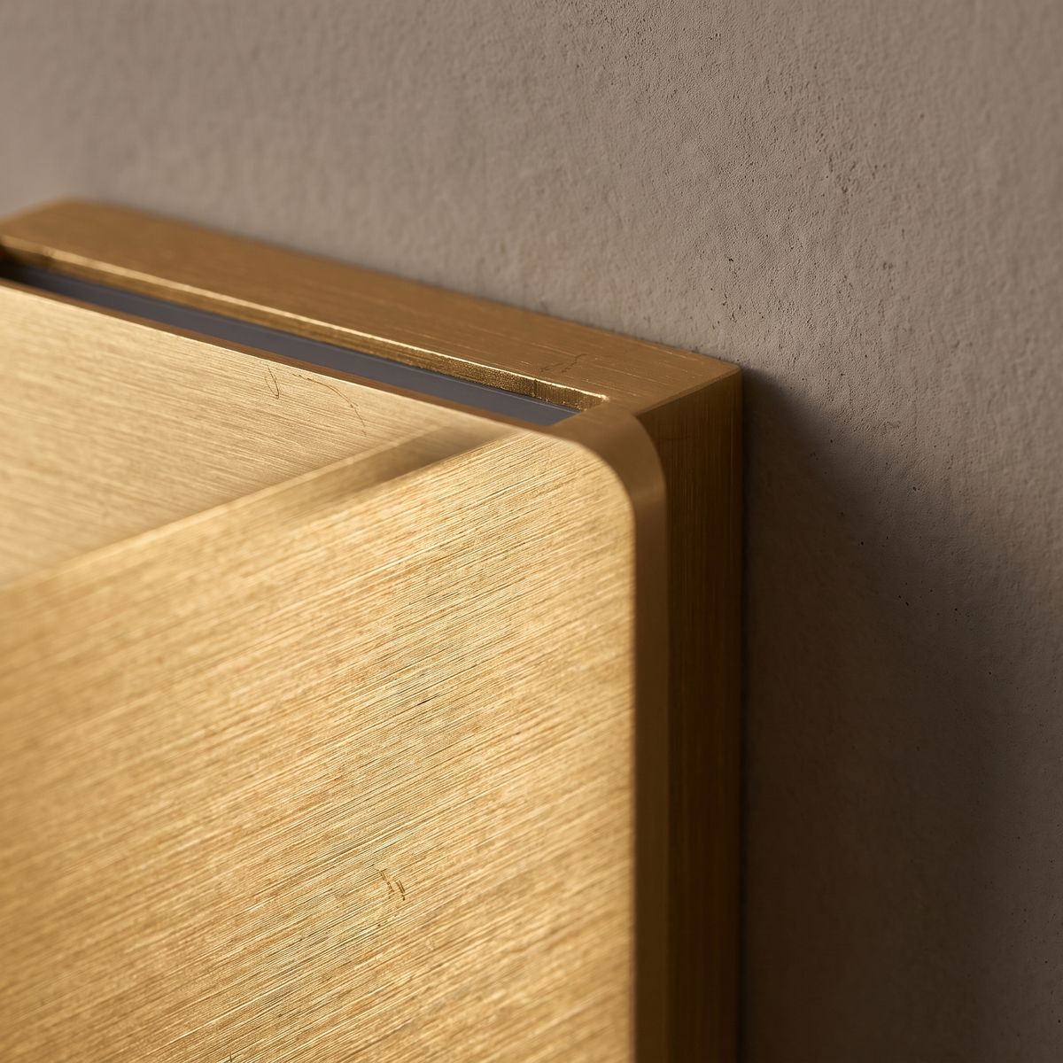 Close-up of the brushed gold anodized aluminum edge and LED light slot on the rectangular flat panel wall sconce