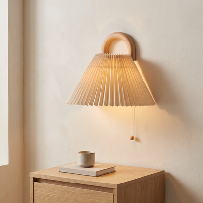 Modern solid beechwood semi-circle wall sconce with beige pleated fabric shade glowing above an oak nightstand