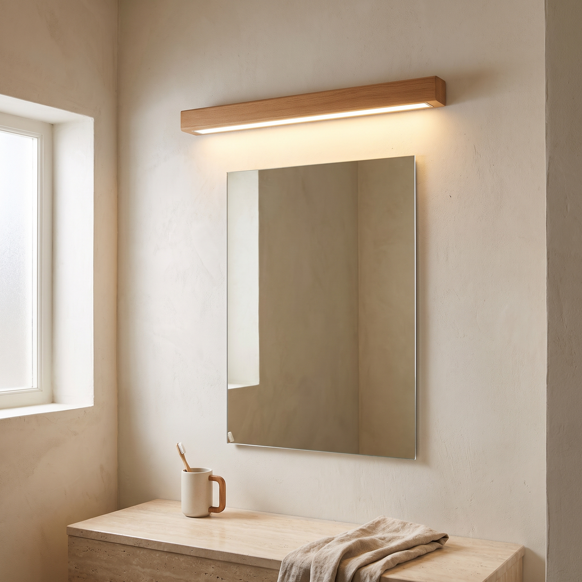 Japanese simple solid wood strip LED wall sconce glowing above a bathroom vanity mirror on a lime-washed plaster wall