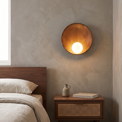 Modern minimalist round wood-grain resin wall sconce with frosted glass globe glowing warm above a walnut nightstand in a bedroom