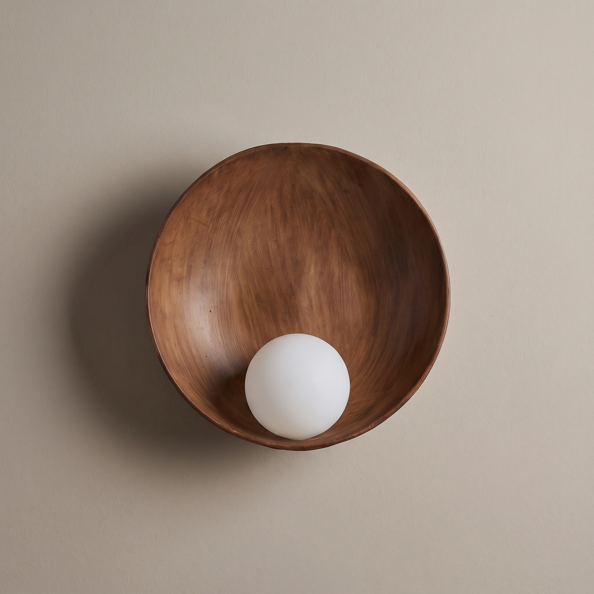 Modern minimalist round wood-grain resin wall sconce with frosted glass globe, lamp off, mounted on a plain greige plaster wall
