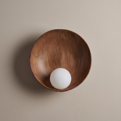 Modern minimalist round wood-grain resin wall sconce with frosted glass globe, lamp off, mounted on a plain greige plaster wall