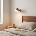 Wooden USB rechargeable magnetic LED night light wall sconce in beech glowing warm beside a walnut headboard in a bedroom