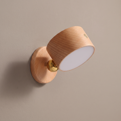 Wooden USB rechargeable magnetic LED night light wall sconce in beech, lamp off, on a plain greige plaster wall showing the brass ball joint and round wall plate
