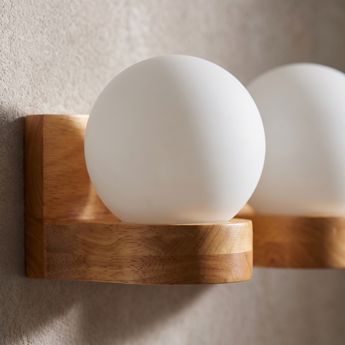 Close-up of the rubberwood grain and opal glass globe on the Nordic wooden wall sconce