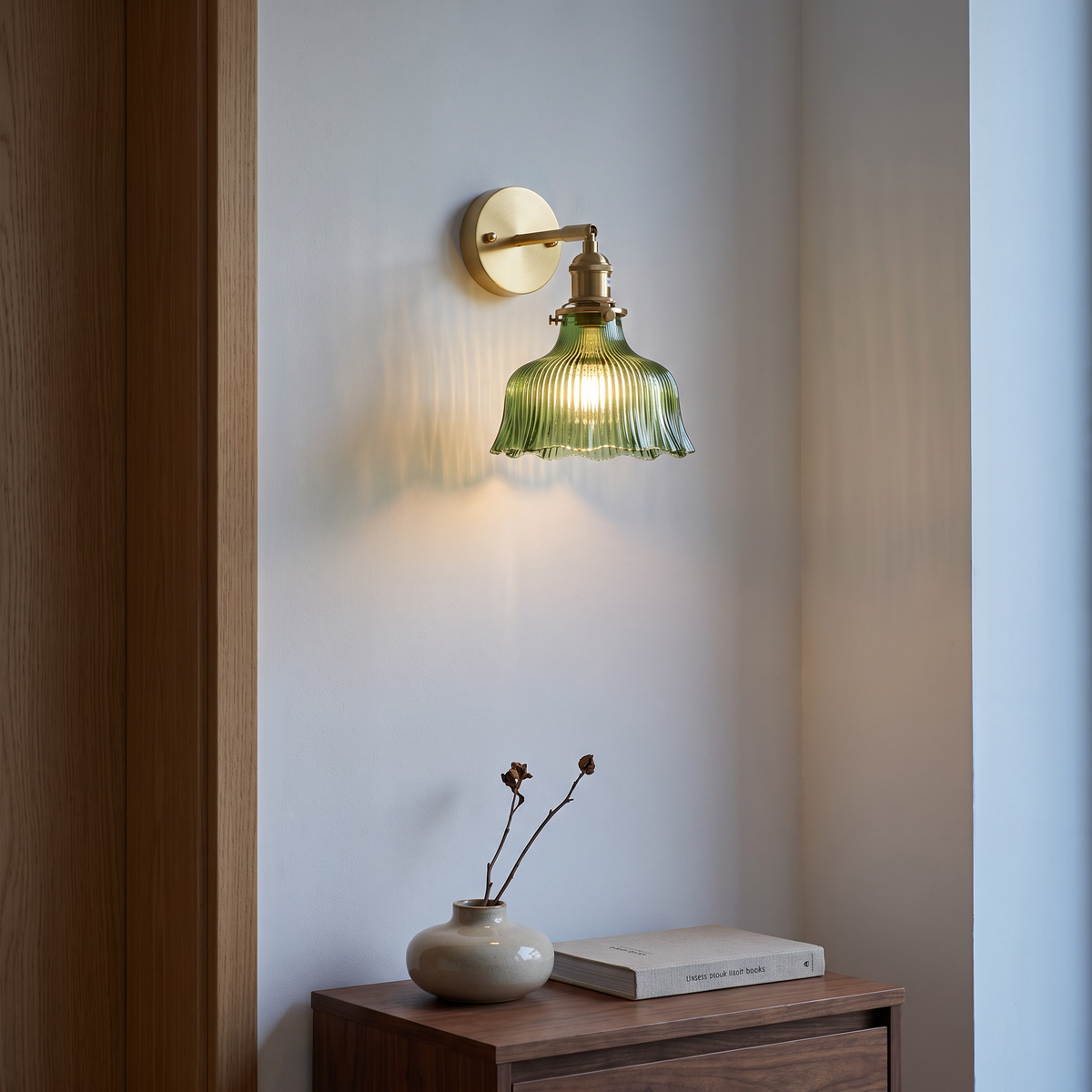 Green glass and brass flower wall sconce lit at dusk above a walnut console in a Nordic living room