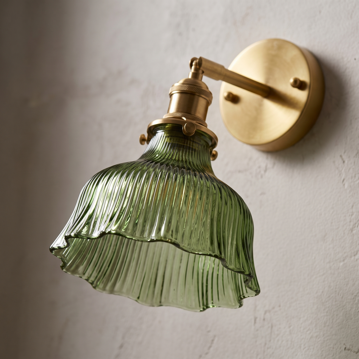 Close-up of the ribbed green glass flower shade and brass fitting on the Nordic copper wall sconce