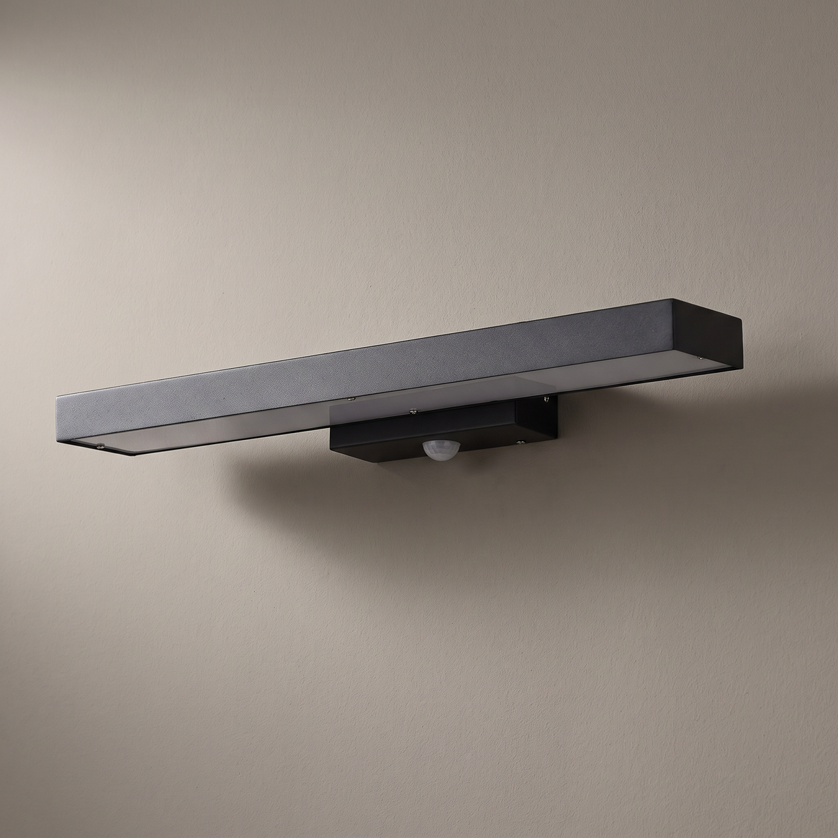 Black flat rectangular waterproof LED sensor outdoor wall light mounted on a plain rendered wall, light off
