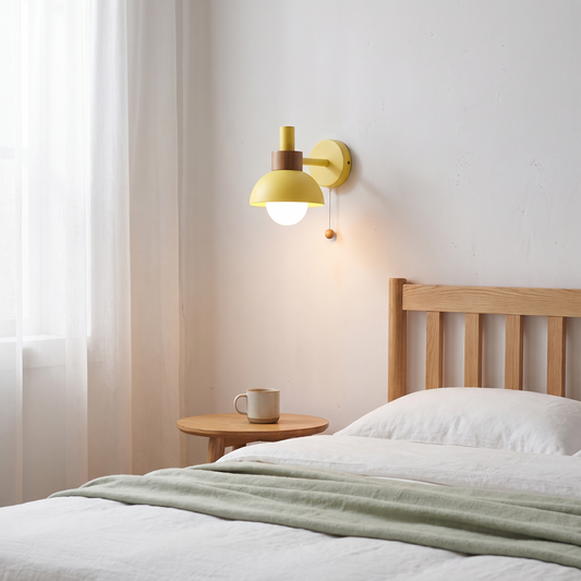 Nordic macaron globe wall sconce in wheat yellow glowing warm beside a light oak bed