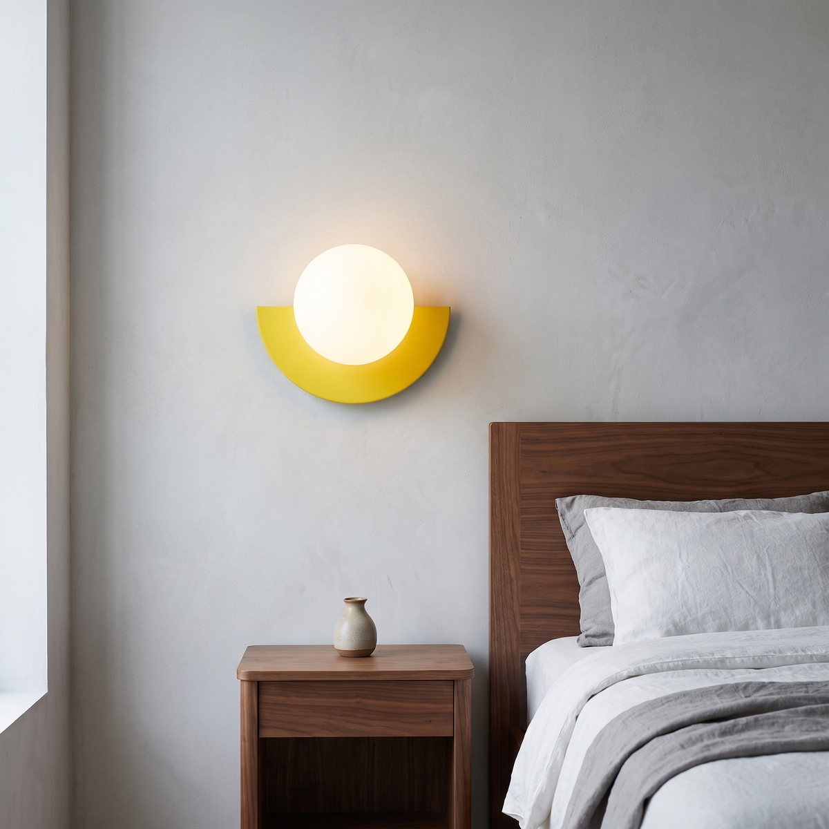 Modern minimalist yellow semicircle glass globe wall sconce glowing warm beside a walnut bed